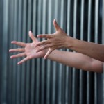 hands reaching through bars